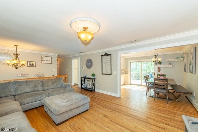 living room with a chandelier, light wood-type flooring, ornamental molding, and baseboards
