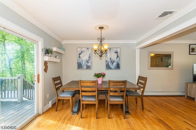 dining area featuring light wood-style floors, baseboard heating, a chandelier, ornamental molding, and baseboards