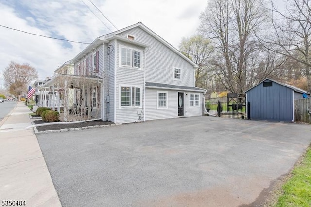 view of home's exterior featuring fence, an outbuilding, driveway, and covered porch