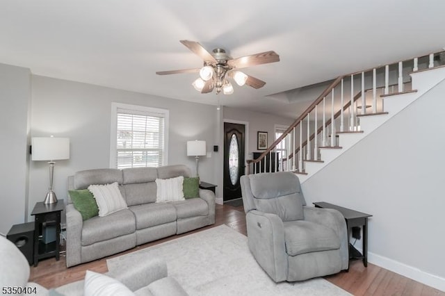 living room with wood finished floors, baseboards, stairs, and ceiling fan