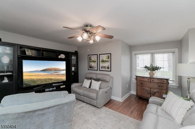 living room featuring baseboards, a ceiling fan, and wood finished floors