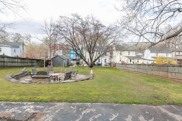 view of yard with a fenced backyard, a residential view, a shed, an outbuilding, and an outdoor fire pit