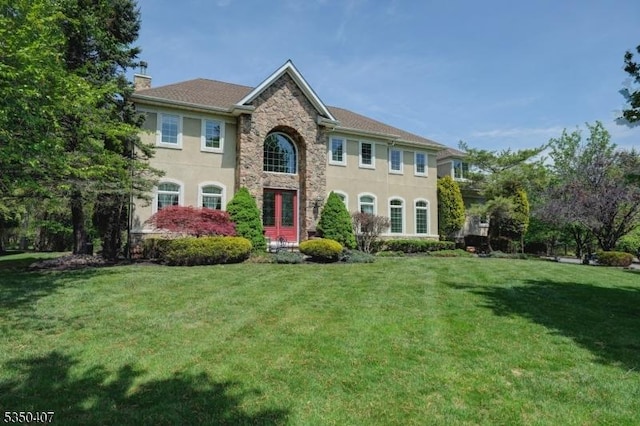 view of front of house with stone siding, stucco siding, a chimney, and a front yard