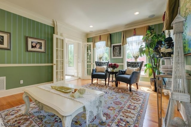 sitting room with ornamental molding, light wood-type flooring, and visible vents