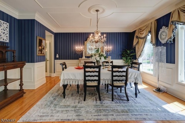 dining area featuring crown molding, a chandelier, a decorative wall, and light wood-style flooring