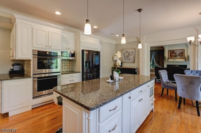 kitchen featuring ornamental molding, white cabinetry, a kitchen island, light wood-style floors, and stainless steel appliances