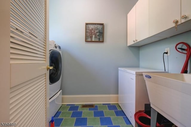 washroom with cabinet space, baseboards, and a sink