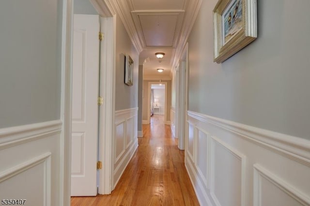 hall featuring attic access, a decorative wall, a wainscoted wall, and ornamental molding