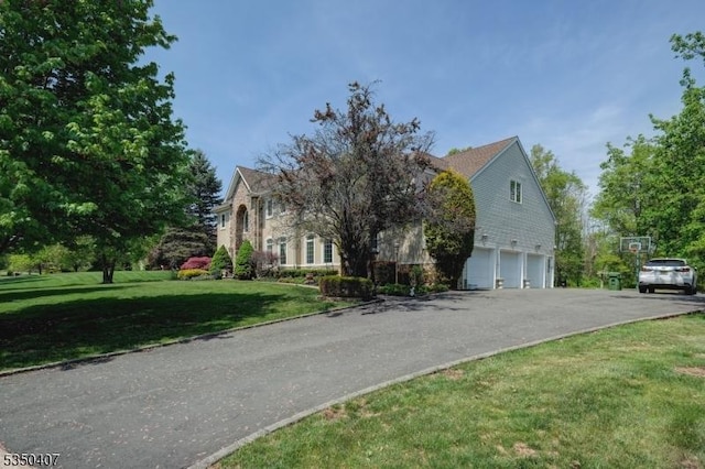 obstructed view of property with an attached garage, a front lawn, and driveway