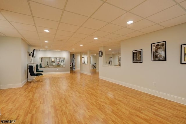 unfurnished living room featuring light wood-type flooring, a drop ceiling, baseboards, and recessed lighting