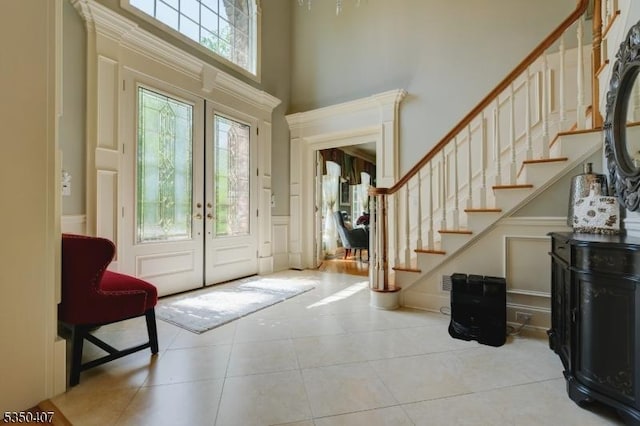 entryway with stairs, tile patterned floors, french doors, and a towering ceiling
