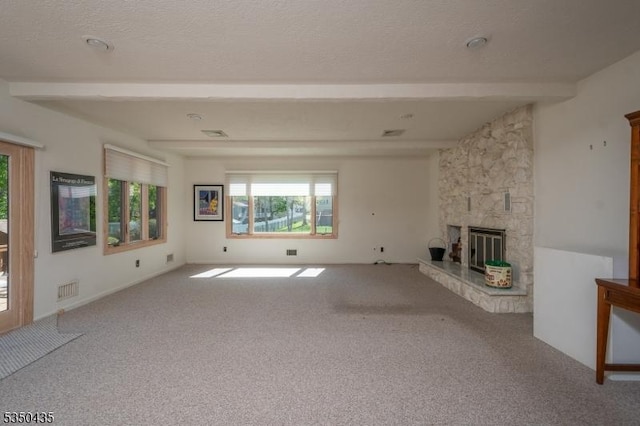 unfurnished living room with carpet floors, visible vents, a stone fireplace, and beamed ceiling