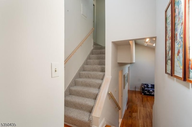 stairway with wood finished floors and a fireplace