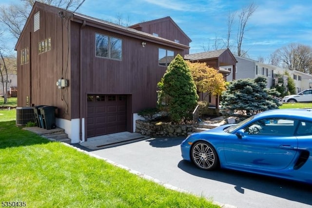 view of side of home featuring a lawn, a garage, central AC, and driveway