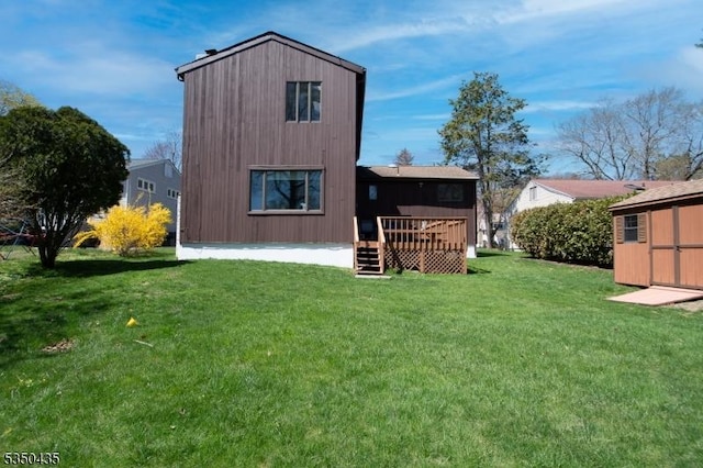 back of house featuring a lawn, a wooden deck, and an outdoor structure