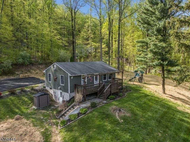 view of front of house with an outdoor structure, a wooden deck, a storage unit, a view of trees, and stairway