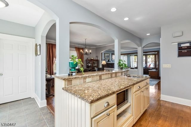 kitchen featuring baseboards, light stone countertops, and cream cabinetry