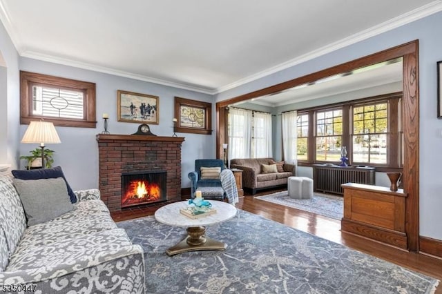 living area featuring ornamental molding, a brick fireplace, and wood finished floors