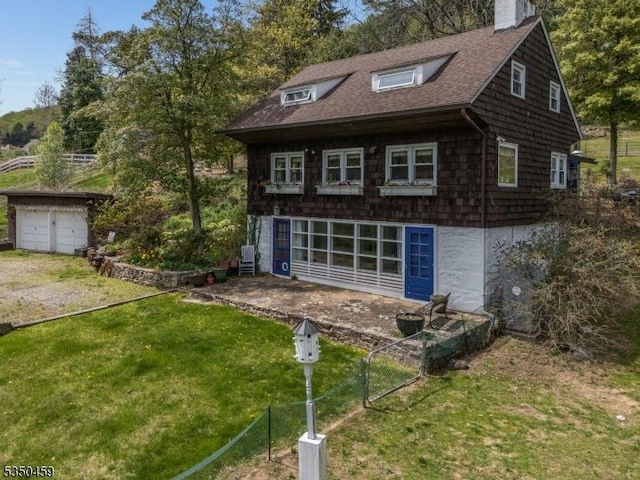 view of front of home featuring roof with shingles, a chimney, a front lawn, and a garage