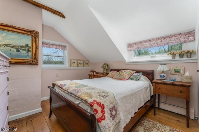 bedroom with multiple windows, lofted ceiling, and hardwood / wood-style floors