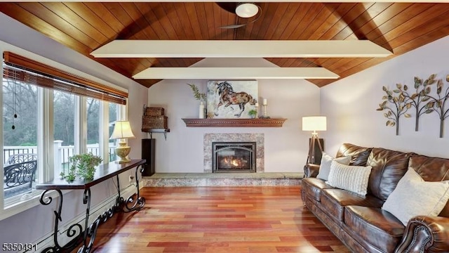 living room featuring lofted ceiling with beams, a premium fireplace, wooden ceiling, and wood finished floors