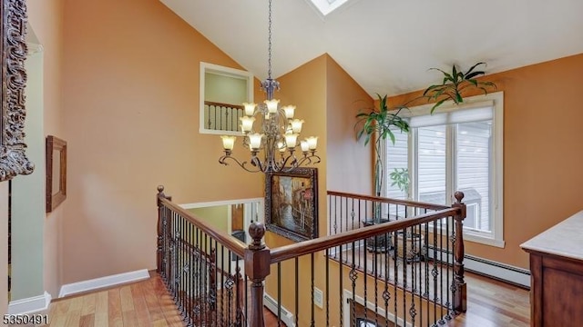 stairway with baseboards, a notable chandelier, lofted ceiling, baseboard heating, and wood finished floors