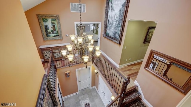 stairs featuring high vaulted ceiling, baseboards, a chandelier, and visible vents