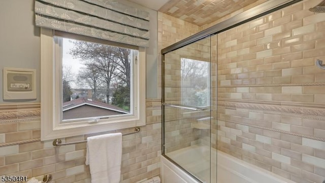 full bathroom featuring shower / bath combination with glass door and tile walls