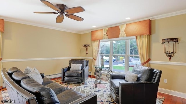 living area with a ceiling fan, wood finished floors, a baseboard heating unit, baseboards, and ornamental molding