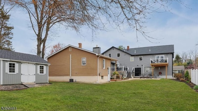 back of property with a yard, an outbuilding, fence, and a deck
