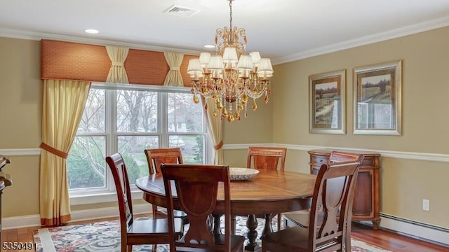 dining room with wood finished floors, visible vents, ornamental molding, a baseboard heating unit, and a notable chandelier