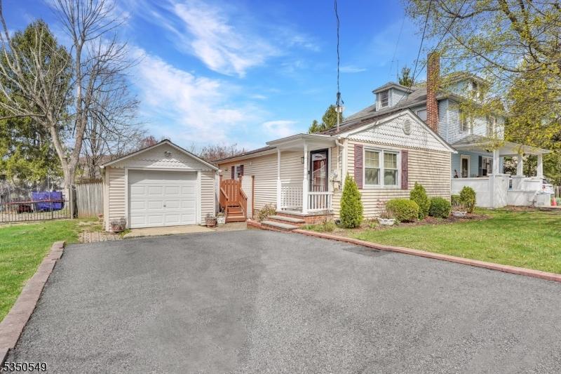 view of front facade with an outdoor structure, a detached garage, aphalt driveway, a front yard, and fence