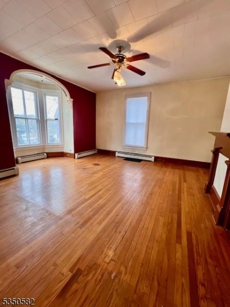 32 High St, Blairstown Twp, NJ 07825 - unfurnished living room with a baseboard radiator, baseboard heating, arched walkways, and light wood finished floors