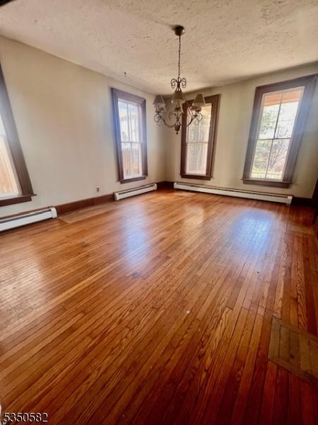 32 High St, Blairstown Twp, NJ 07825 - unfurnished dining area featuring a chandelier, wood-type flooring, healthy amount of natural light, a textured ceiling, and baseboard heating