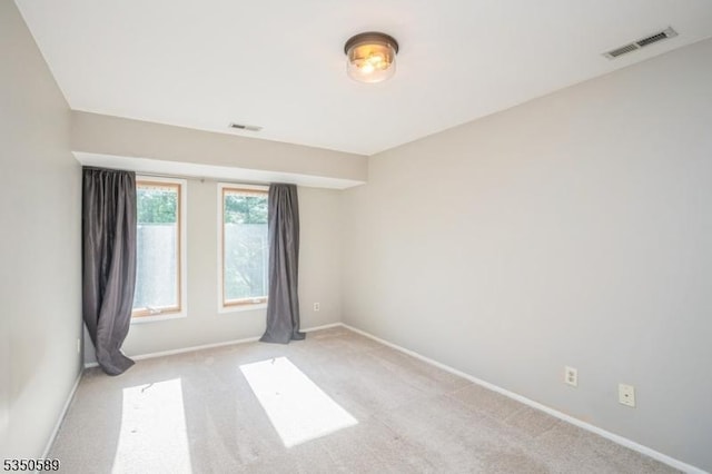 spare room with light colored carpet and baseboards