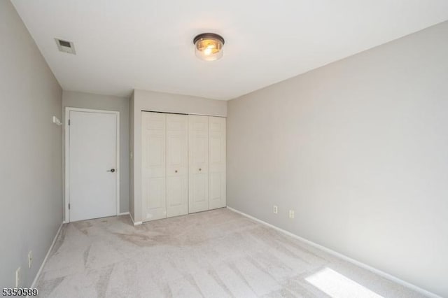 unfurnished bedroom featuring light colored carpet, a closet, and baseboards