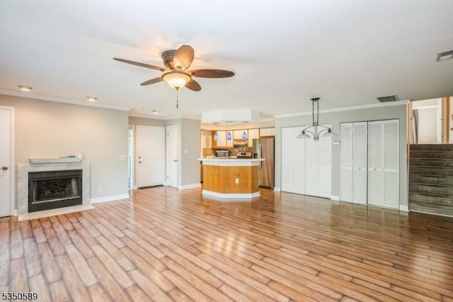 unfurnished living room with a ceiling fan, stairs, a fireplace, baseboards, and ornamental molding