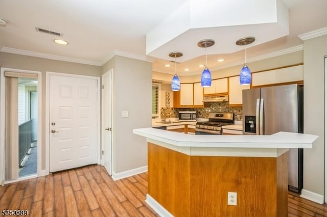 kitchen with stainless steel appliances, under cabinet range hood, light countertops, light wood-type flooring, and crown molding