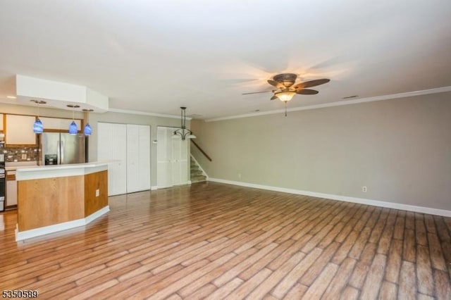 unfurnished living room featuring ceiling fan, light wood-style floors, stairway, ornamental molding, and baseboards