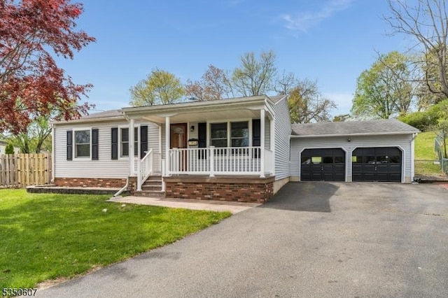 view of front of property featuring fence, covered porch, a front lawn, and aphalt driveway