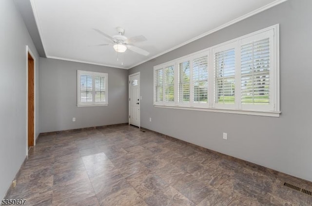 empty room with baseboards, ornamental molding, a ceiling fan, and visible vents