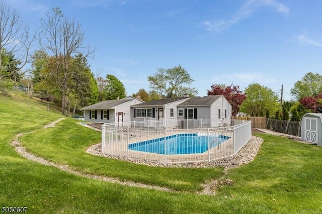 view of pool featuring a storage shed, a lawn, an outbuilding, and a fenced backyard