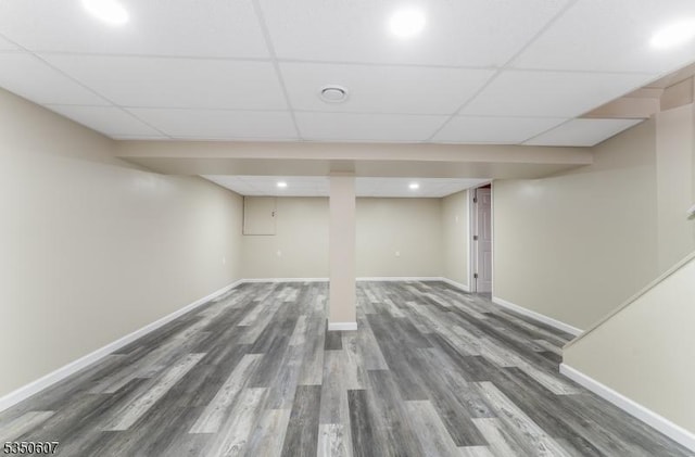 finished basement featuring recessed lighting, baseboards, a paneled ceiling, and wood finished floors