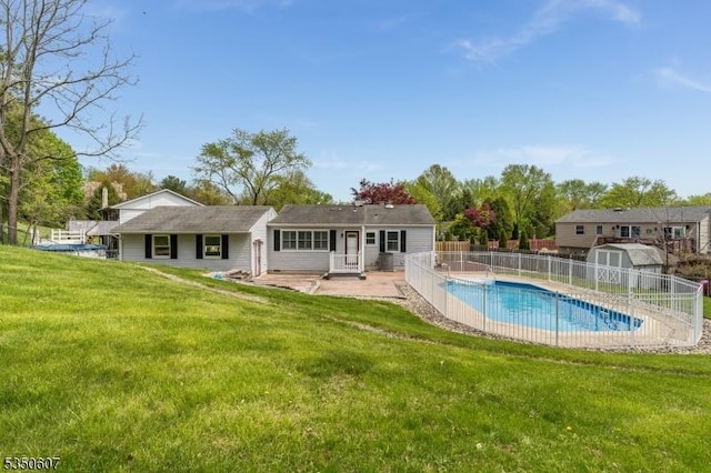 view of pool with fence, a yard, a fenced in pool, a storage unit, and an outbuilding