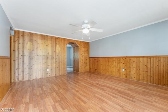 unfurnished room with arched walkways, ceiling fan, wood finished floors, and wood walls