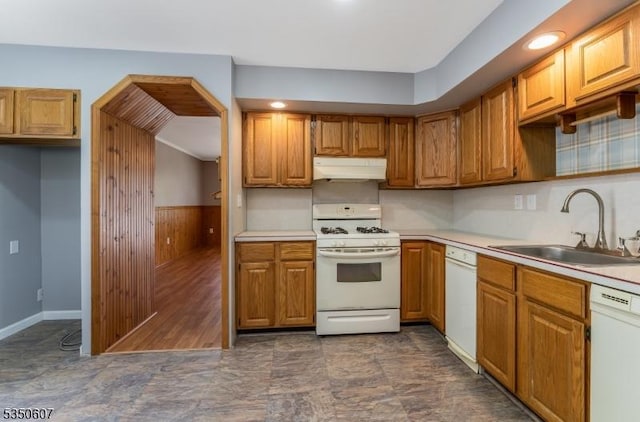 kitchen featuring a sink, brown cabinets, under cabinet range hood, and white appliances