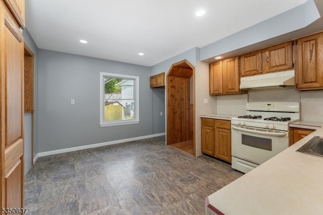 kitchen with brown cabinetry, white range with gas stovetop, recessed lighting, light countertops, and under cabinet range hood