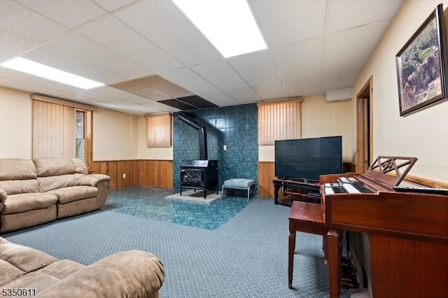 carpeted living area featuring wainscoting, wood walls, and a wood stove