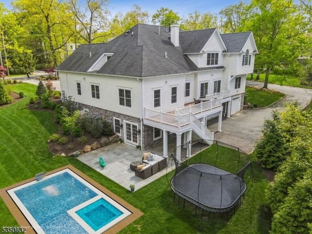 260 Hartshorn Dr, Millburn Twp, NJ 07078 - back of house featuring a patio, a lawn, a trampoline, a chimney, and an attached garage