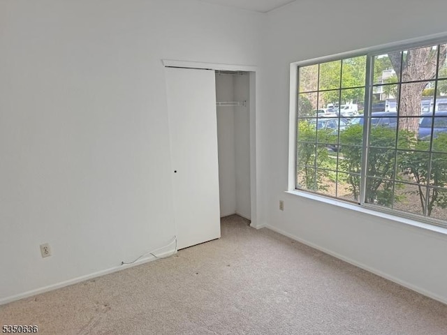 unfurnished bedroom featuring a closet, carpet, baseboards, and multiple windows